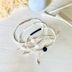 two headphones and a golf ball on a white surface with some hair in the background