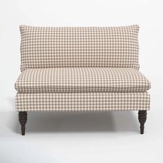 a brown and white checkered couch sitting on top of a wooden leg rester