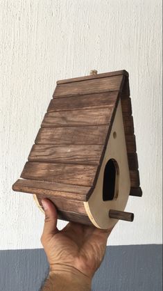 a hand holding up a birdhouse made out of wood