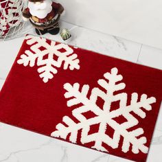 a red and white rug with snowflakes on it next to a christmas tree