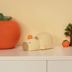 there is a toy mouse and an orange on the shelf next to eachother