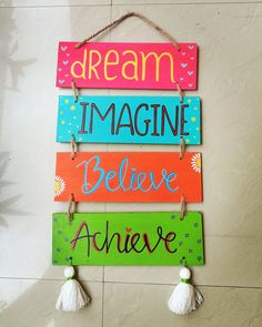 a sign that says dream, imagine, believe and achieve hanging from a wall with tassels