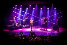 a group of people standing on top of a stage next to each other in front of purple lights