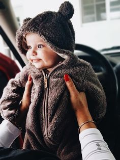 a woman holding a small child in a car seat