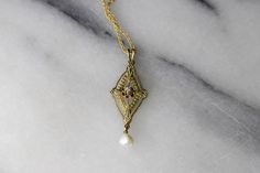 "Antique Edwardian era lavaliere charm made of 14k gold. The charm has an openwork design with stamped details including small flowers at each corner. The center of the charm gold a small diamond in a buttercup setting. At the bottom hangs a natural looking pearl. Era: Edwardian Markings: 14k Material: 14k gold, diamond, pearl Measurements: 32.5mm x 12.8mm. Comes with a new 18\" gold filled chain. Condition: Excellent antique condition with minor surface wear from age Shipping is free in the Uni Victorian 14k Gold Jewelry With Vintage Charm, Ornate Gold Jewelry With Rose Cut Diamonds, Elegant Yellow Gold Jewelry With Vintage Charm, Elegant White Gold Necklace With Vintage Charm, Vintage 14k Gold Filigree Necklace, Vintage 14k Gold Necklace With Intricate Design, Ornate 14k Antique Gold Jewelry, Ornate 14k Gold Antique Gold Jewelry, Ornate Antique Gold 14k Jewelry