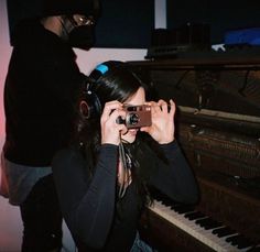 a woman taking a photo in front of an old piano with headphones on her ears