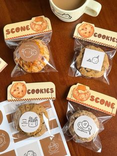 cookies in plastic bags sitting on top of a wooden table next to a cup of coffee