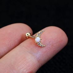 a person's hand holding a gold nose ring with an moon and stars on it