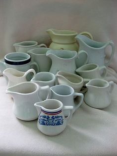 a pile of white and blue pitchers sitting on top of a bed next to each other