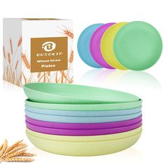 six colorful plates are stacked next to a cardboard box and wheat on the ground with it's packaging