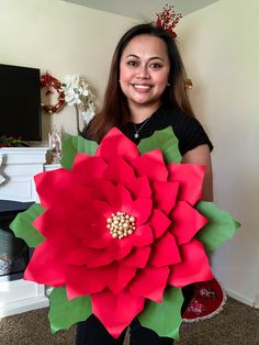 a woman holding a large red flower in her hands