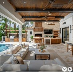 a living room with couches and a fireplace next to a swimming pool in the background