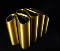 three shiny gold vases sitting next to each other on a black surface with dark background