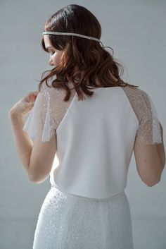 This crop top features a double bias cut satin bodice (no bust darts!) and wide, sparkly beaded raglan sleeves and a crew neck. We recommend strapless bra underneath this wedding crop top. Only available in the shown IVORY color. Please be aware that your veil or other items can stick to this top's sleeves due to sequins, it can also stick together a little bit at times, and you may lose some beads or sequins while wearing it - it is perfectly normal and won't be noticeable in grand scheme of th Fitted White Top For Bridesmaid, White Fitted Top For Bridesmaids, Fitted Short Sleeve Top For Wedding, Elegant Cropped Crop Top For Wedding, Elegant Cropped Tops With Sheer Sleeves, Elegant Embellished Wedding Crop Top, Evening Crop Top With Sheer Sleeves, Fitted Wedding Top With Sheer Bodice, Wedding Tops With Lace Sleeves