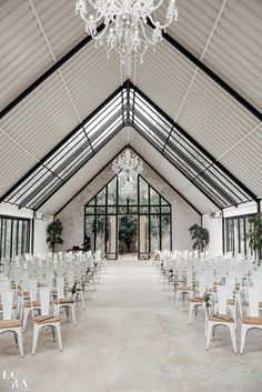 a room filled with lots of white chairs and chandelier hanging from the ceiling