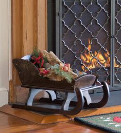 a wooden sleigh with christmas decorations on it in front of a fire place