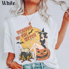 a woman wearing a white t - shirt that says season of the witch on it