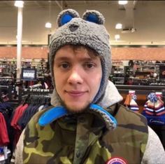 a young man wearing a hat and jacket in a store with other items on the shelves