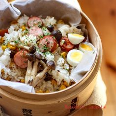 a wooden bowl filled with rice, beans and sausage next to an egg on top