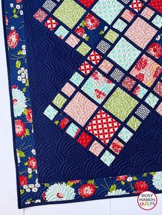 a blue quilt with red, white and green squares on it's sides is shown