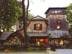 a large house with lots of windows and plants on the front yard, surrounded by trees