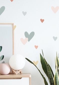 a potted plant next to a wall with hearts on it and a mirror in the corner