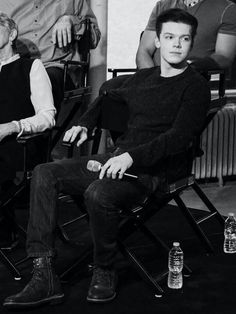 black and white photograph of two men sitting in chairs with bottles on the floor next to them