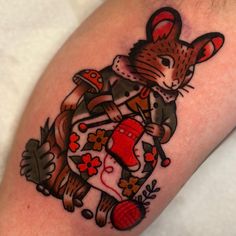 a tattoo with an image of a cat on it's arm, holding a yarn ball and knitting needles