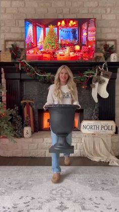 a woman standing in front of a fire place holding a large pot with the word north pole on it