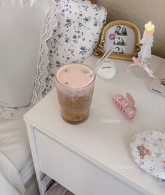 a table topped with a cup filled with liquid next to a candle and other items