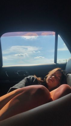 a woman laying in the back seat of a car with her eyes closed and head down