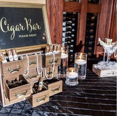 a table topped with wooden drawers filled with candles and jewelry boxes next to a chalkboard sign