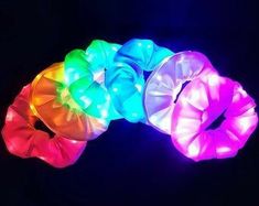 four different colored hair ties are shown in the dark with light up colors on them