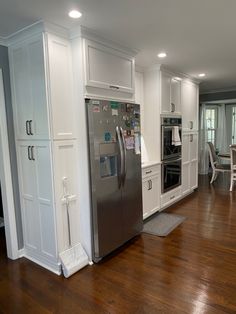 a large kitchen with white cabinets and stainless steel refrigerator freezer combo in the center