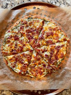 a pizza sitting on top of a wooden pan covered in cheese and bacon toppings