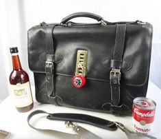 a black leather briefcase sitting on top of a table next to a bottle of beer