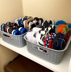 two baskets filled with pairs of shoes on top of a white shelf next to a wall