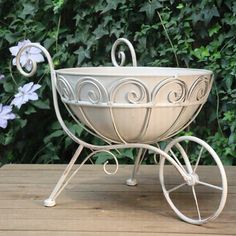 a white metal flower pot sitting on top of a wooden table