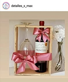 a bottle of wine in a wooden box with a pink bow on the side and a glass next to it