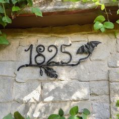 a house number sign on the side of a stone building with vines growing around it