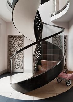 a spiral staircase in the middle of a room with white walls and black metal railings