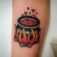 a black and red tattoo on the arm of a person with a pot full of fire