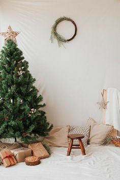 a small christmas tree sitting on top of a bed next to a wooden step stool