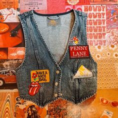 Available in a dark blue wash, this patched retro vest gets finished off with a button-down front closure, gingham stitched pockets, and a cropped length. -Cotton -Patches will vary and pocket color too! -Penny Lane patch will appear in all of them. Patch Vest, Retro Vest, Button Vest, Summer 2025, Vest And Tie, Jean Vest, Penny Lane, Clothing Ideas, Blue And Black