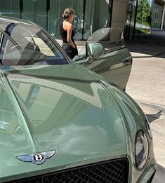 a woman standing next to a green sports car in front of a glass storefront