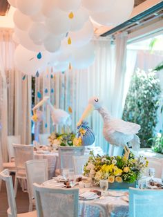 a table set for a party with balloons and flowers on the tables in front of it