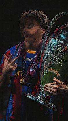 a close up of a person holding a soccer trophy in front of his face with both hands