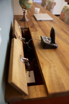 an open drawer in the middle of a table with a phone and laptop on it