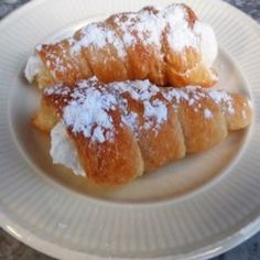 two pastries on a plate covered in powdered sugar