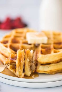 a stack of waffles on a plate with syrup and butter being drizzled over them